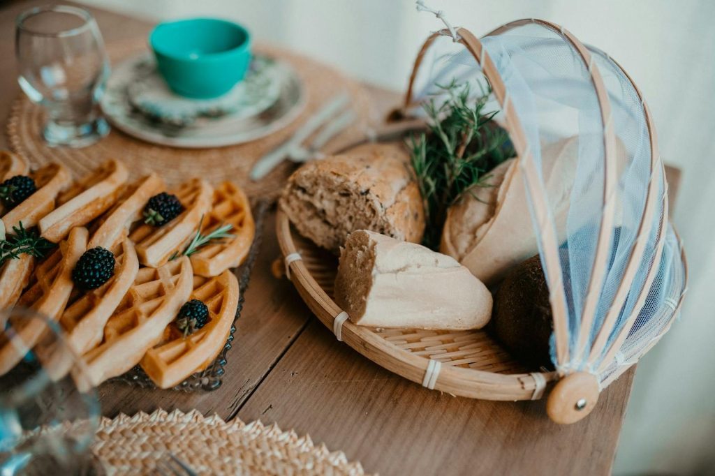 A cozy breakfast with waffles, blackberries, and fresh bread on a wooden table.