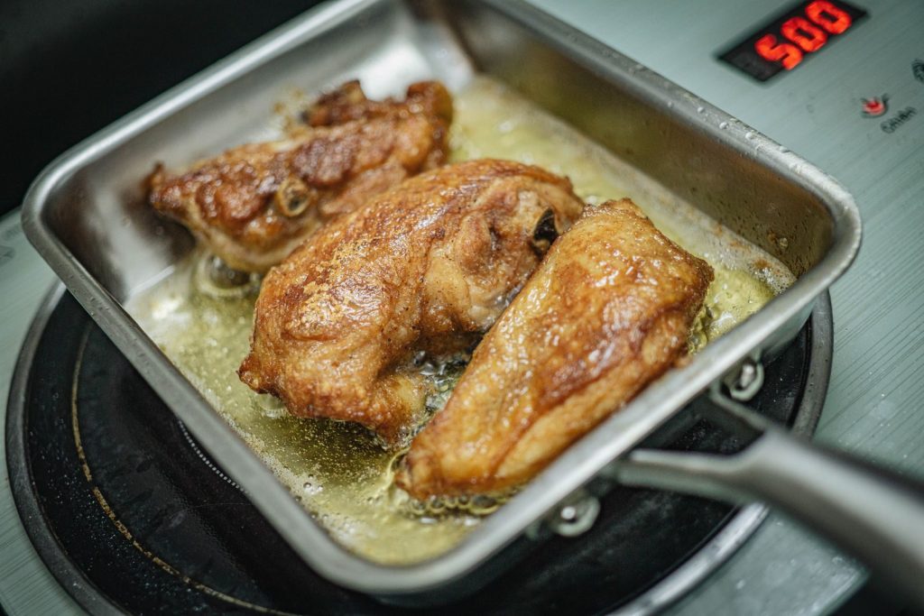 Golden brown chicken frying in a pan on a stovetop for a delicious meal.