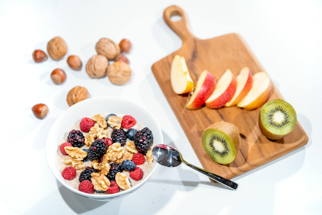 A nutritious breakfast bowl featuring fresh berries and walnuts, served with sliced fruit and kiwi.