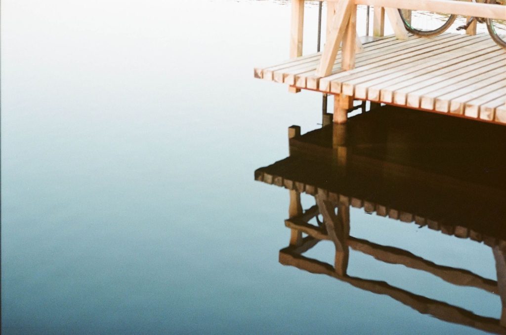 A peaceful scene of a wooden dock reflecting on calm water, showcasing serene natural beauty.