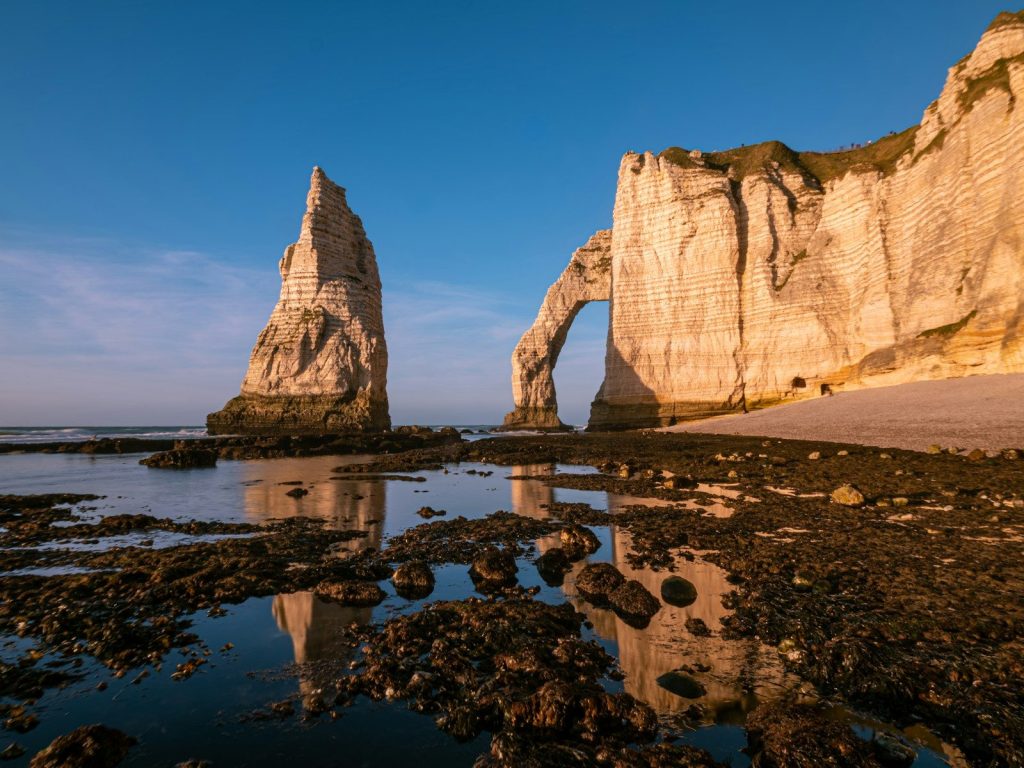 White cliffs, a natural arch, and sea stack at sunset.
