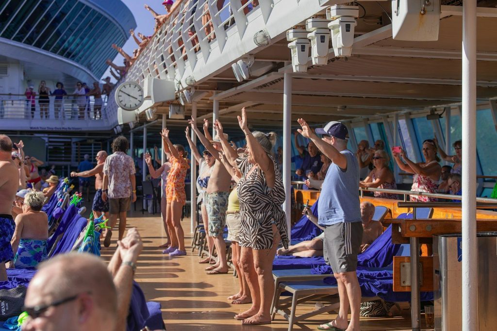 People raising hands on a sunny cruise ship deck.