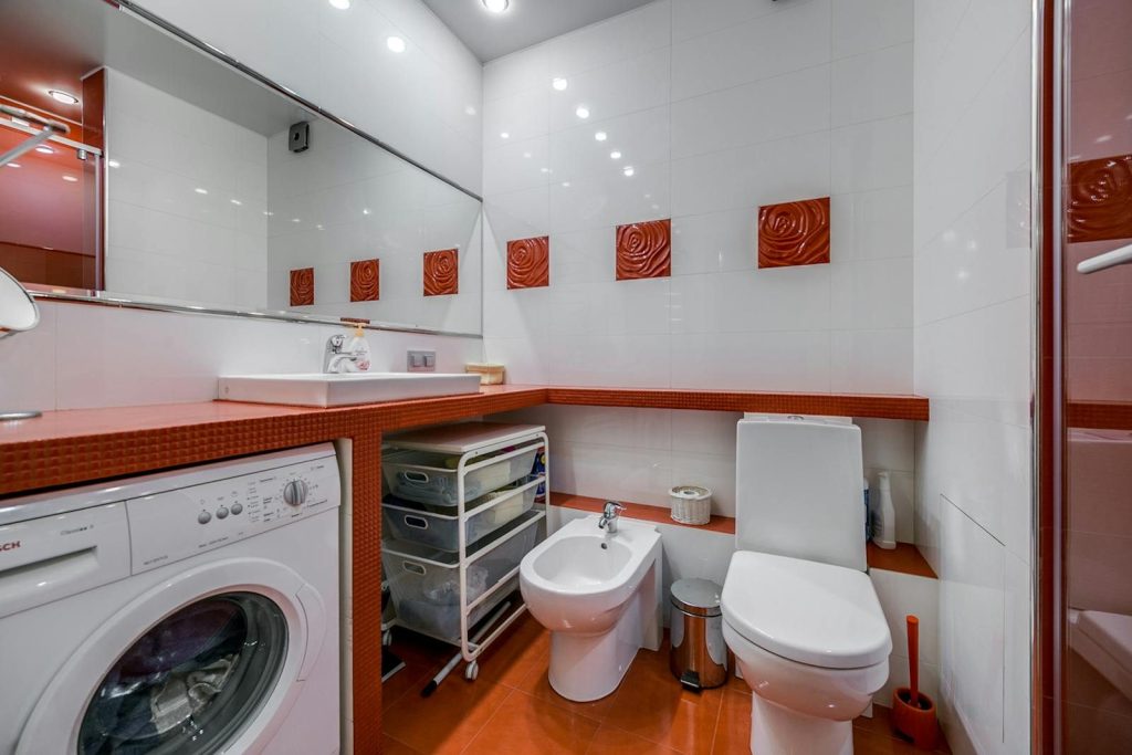 Stylish bathroom with toilet, bidet, and washing machine in a modern design.