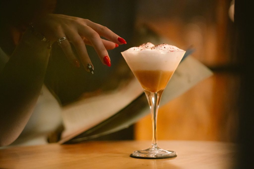 A stylish cocktail with a foam top, elegantly presented in a dimly lit bar setting, exuding sophistication.