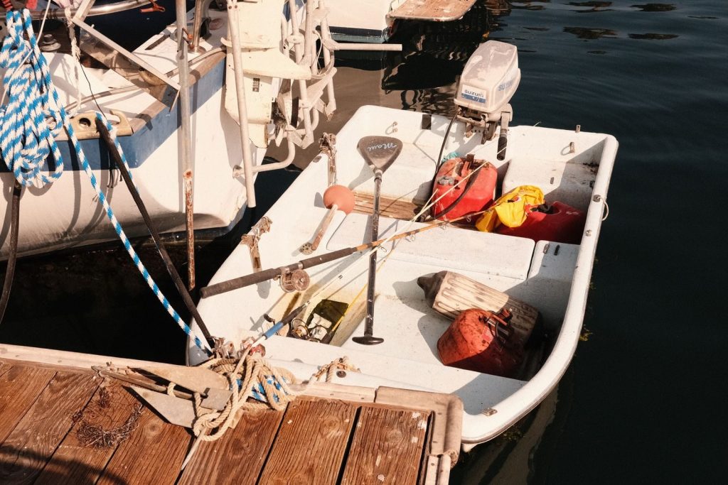 A small boat tied up at a marina dock with nautical equipment on a sunny day.