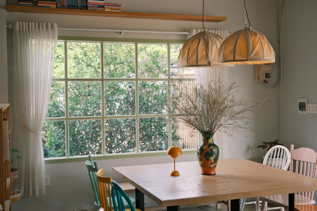 Bright dining room featuring a rustic table, colorful chairs, and natural light.