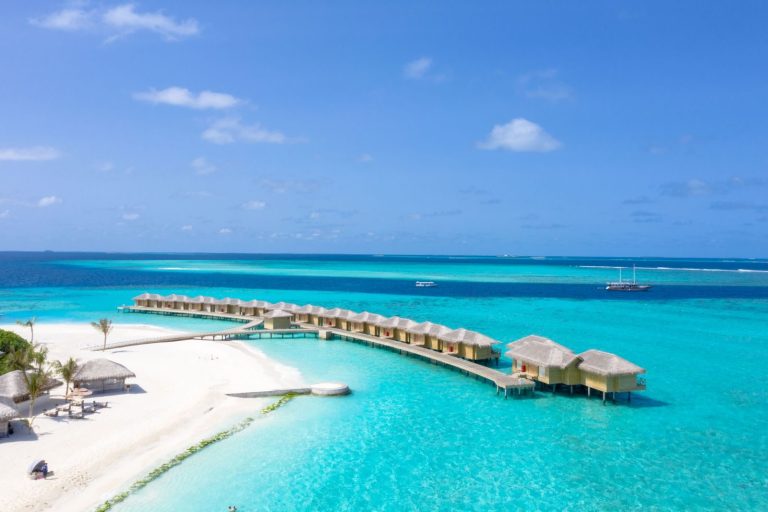 Stunning beachfront resort with overwater bungalows and turquoise waters, perfect for a summer vacation.