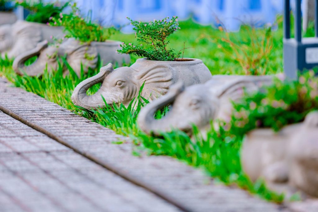 Line of elephant-shaped planters with greenery on a garden path.