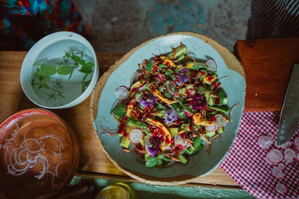 Vibrant summer salad featuring edible flowers, fresh vegetables, and herbs.
