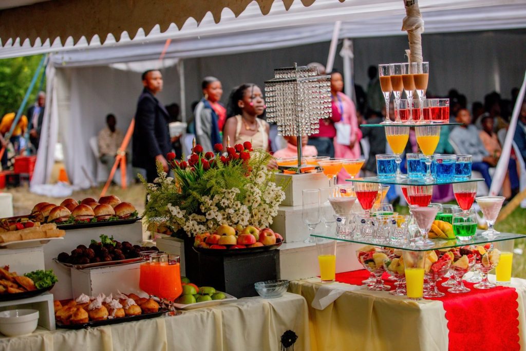 Elegant outdoor buffet setup with vibrant drinks and food at a wedding event.