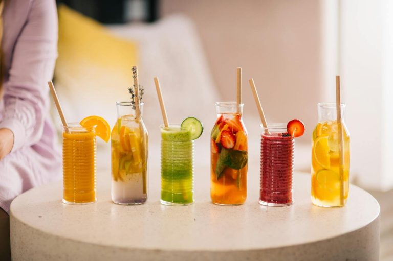 A variety of refreshing fruit drinks in jars with straws arranged on a table.