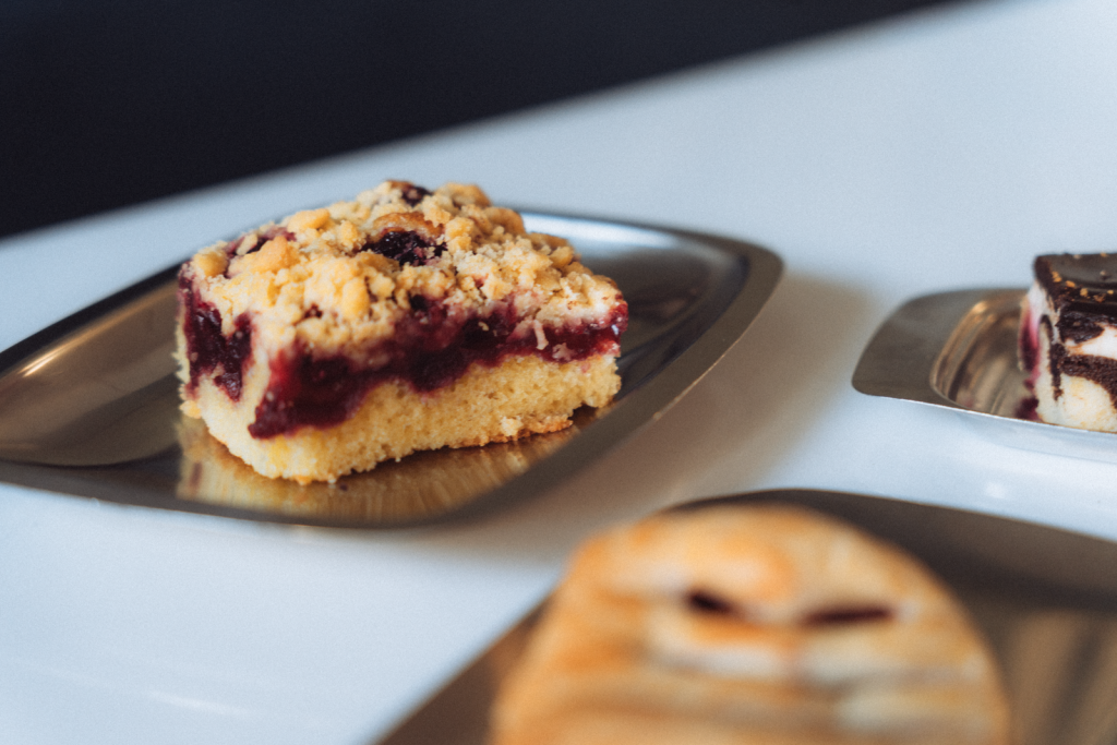 Close-up of a piece of streuselkuchen with berry filling on metal plate.