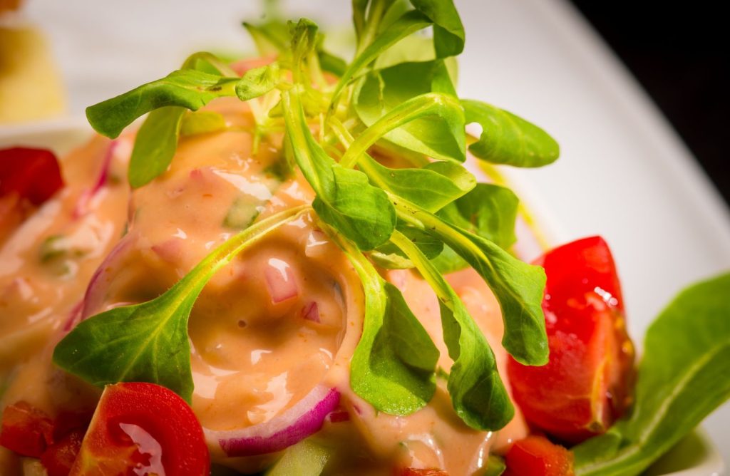 Close-up of a colorful salad with cherry tomatoes and dressing.