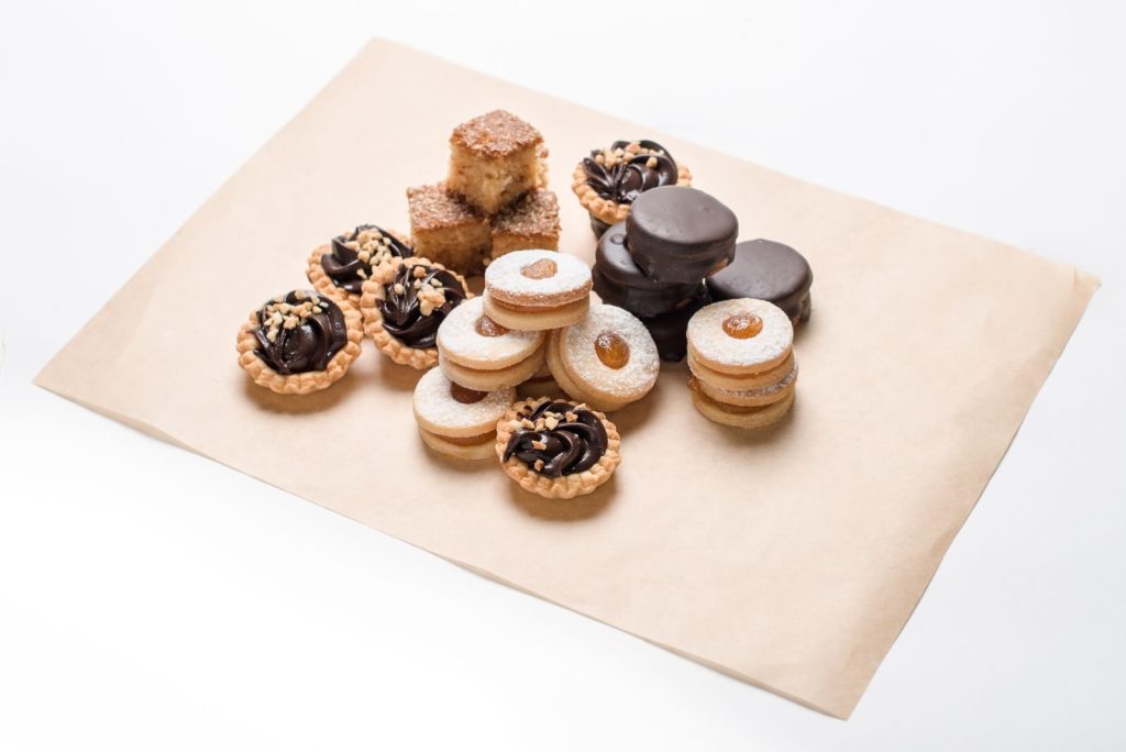 Selection of assorted sweet pastries and cookies on a parchment paper, perfect for dessert lovers.