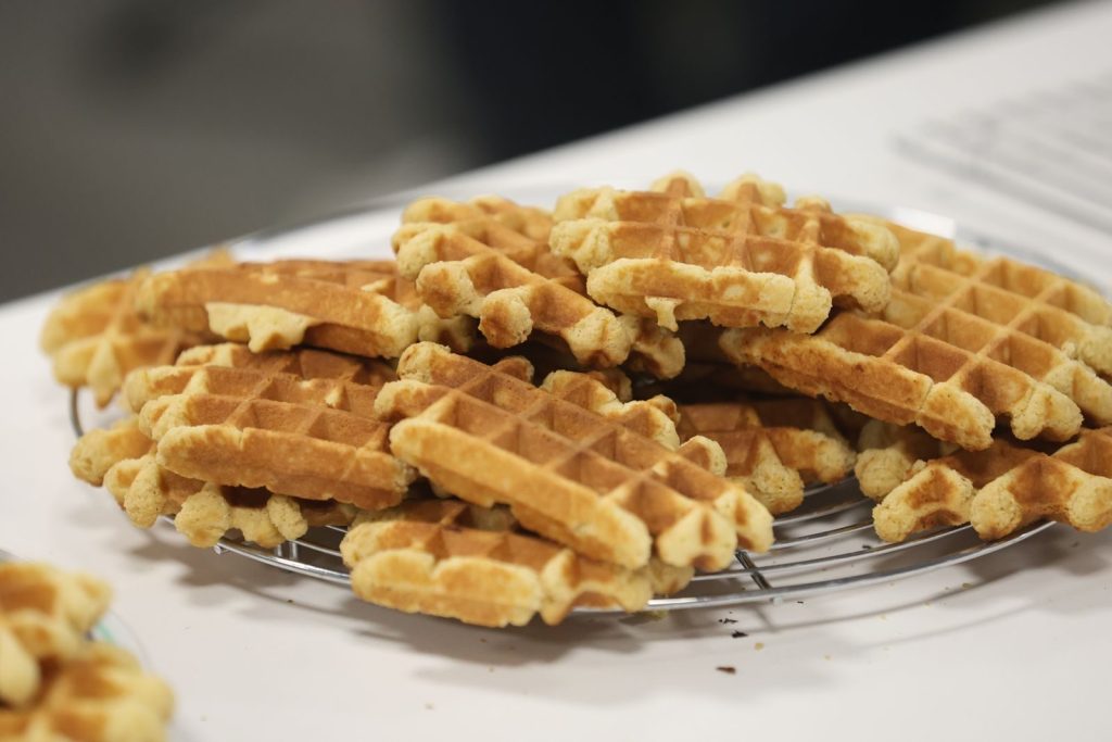 Golden brown waffles stacked on a cooling rack, perfect for breakfast or brunch.
