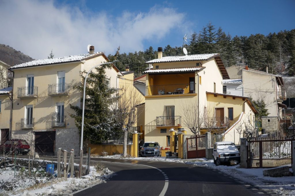 Picturesque village street with snowy rooftops and trees in a winter setting.