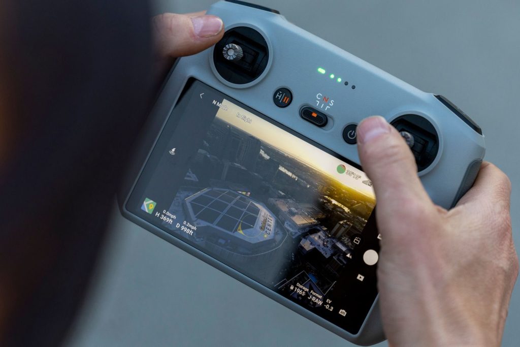 Close-up of a drone controller showing a cityscape view, captured during sunset, reflecting modern technology in action.