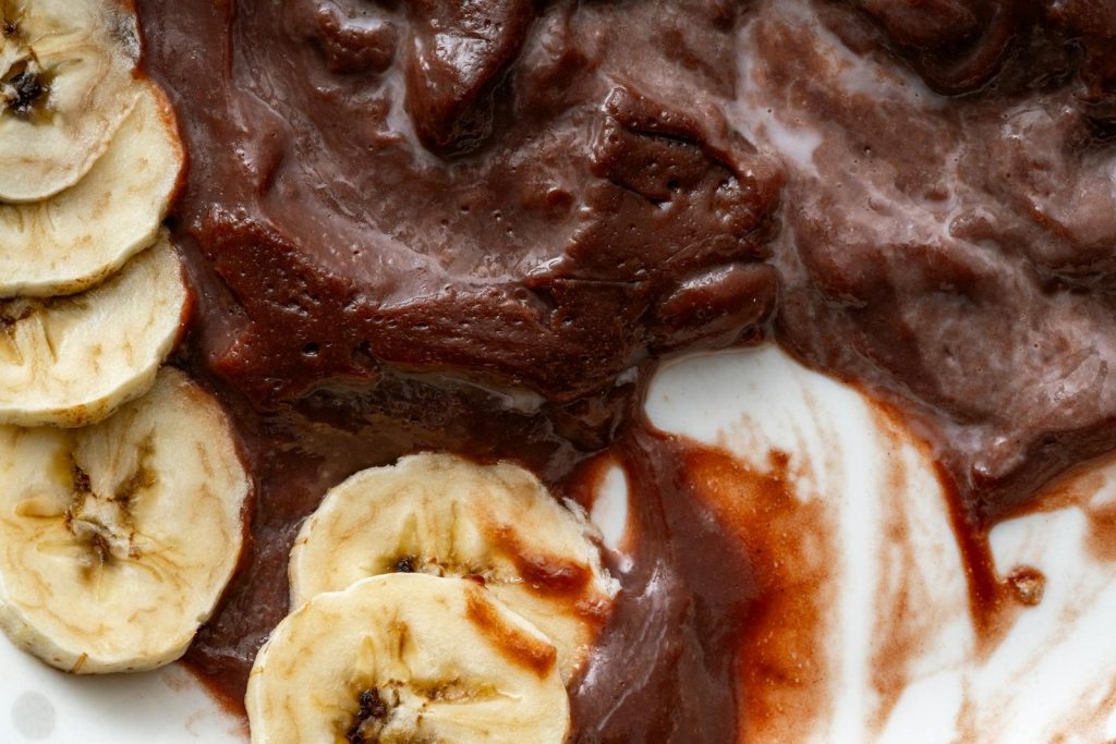 Close-up of banana slices with rich chocolate spread on a white plate, highlighting textures and contrast.