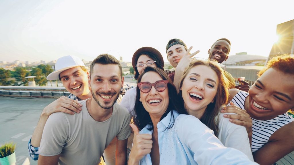 Happy diverse friends taking a selfie on a rooftop in the daytime.