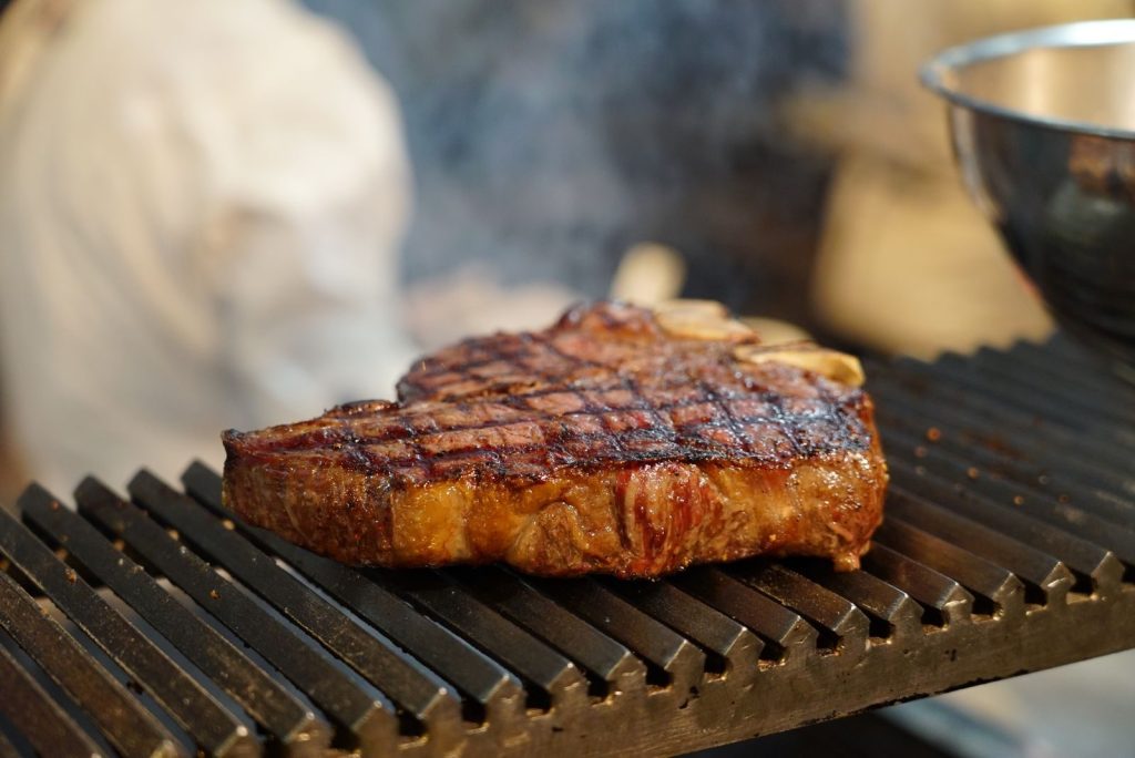 Juicy steak with grill marks sizzling on a barbecue grill, perfect for meat lovers.