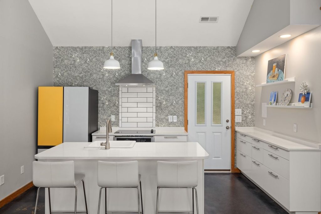 A sleek modern kitchen features a white island, vibrant fridge, and elegant lighting for a contemporary look.