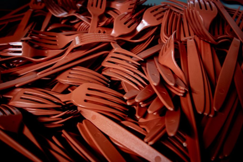Detailed shot of red plastic forks and knives piled together. Perfect for recycling or waste concept.