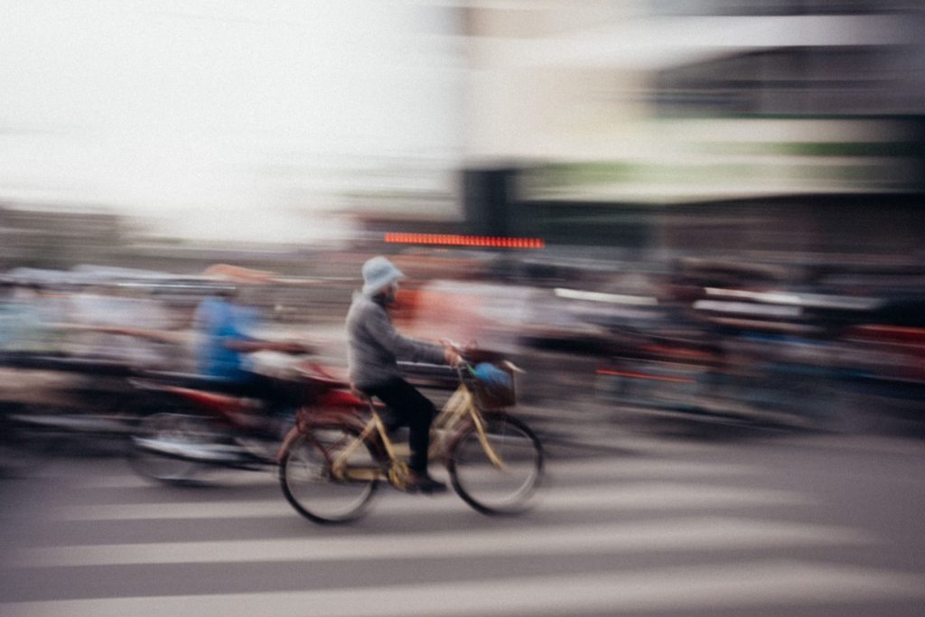 Blurred motion of cyclist amidst bustling traffic in Hà Nội, Vietnam.