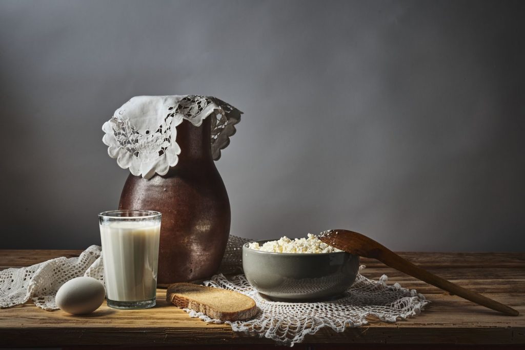 Rustic dairy still life featuring milk, cottage cheese, and bread on a wooden table.