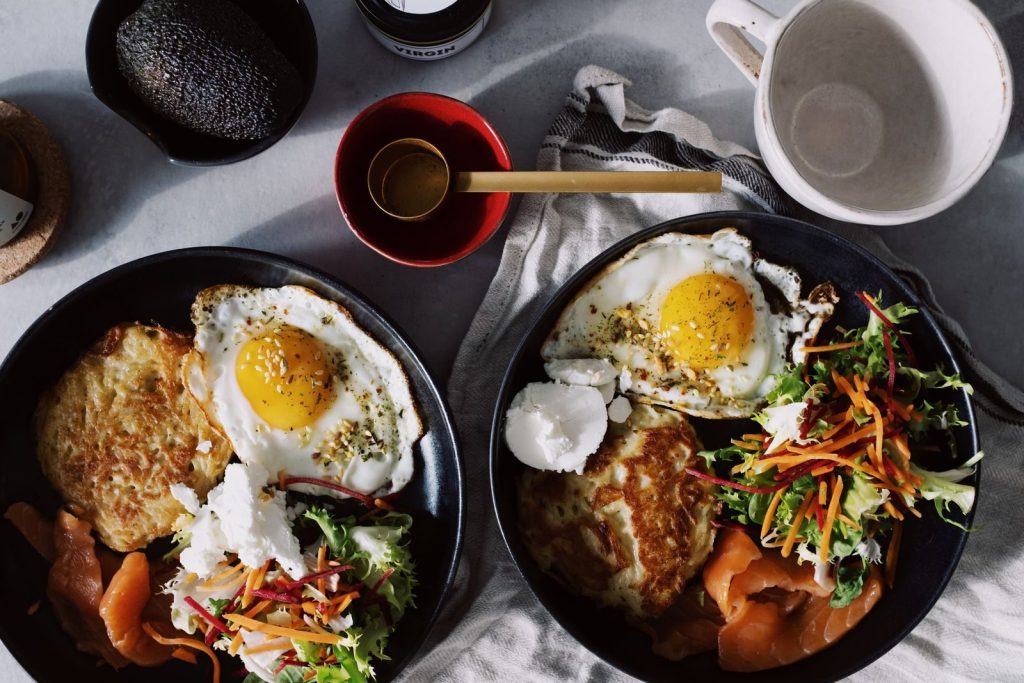 A vibrant brunch spread featuring eggs, smoked salmon, salad, and flatbread.