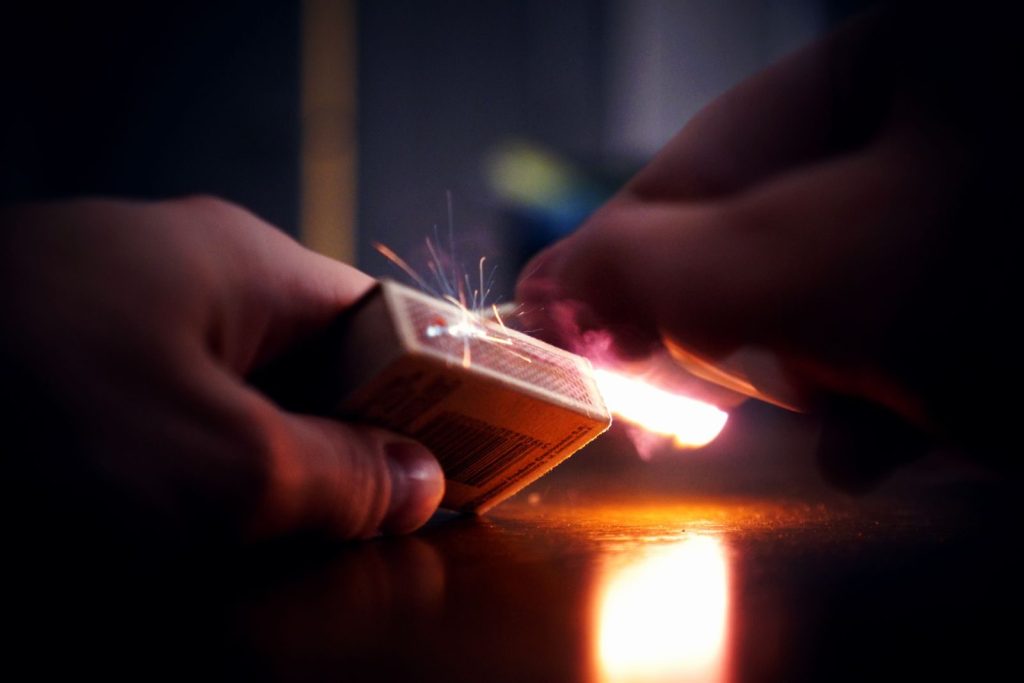 Detailed shot of a match being struck with visible sparks and light illumination.