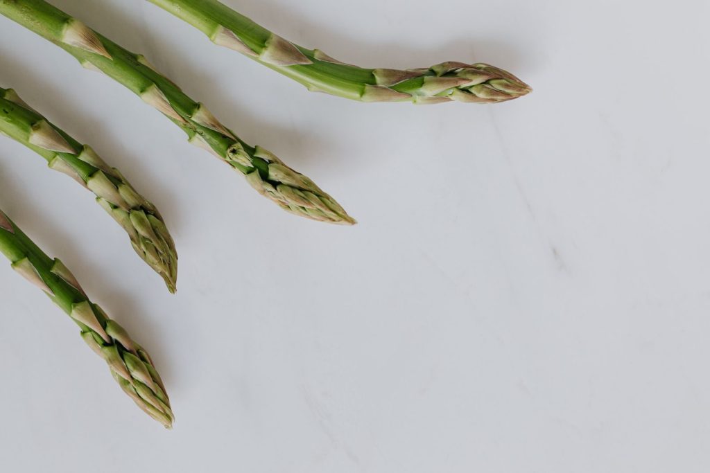 Close-up of fresh asparagus tips on a white background, highlighting freshness and healthy eating.