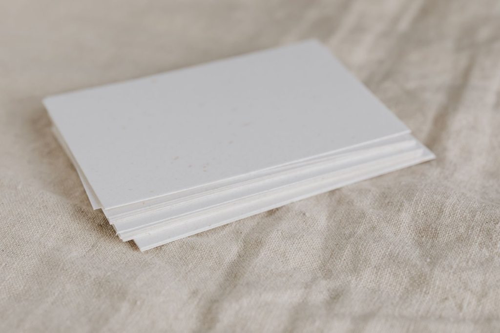 Stack of white paper on textured fabric surface, perfect for minimalistic designs.