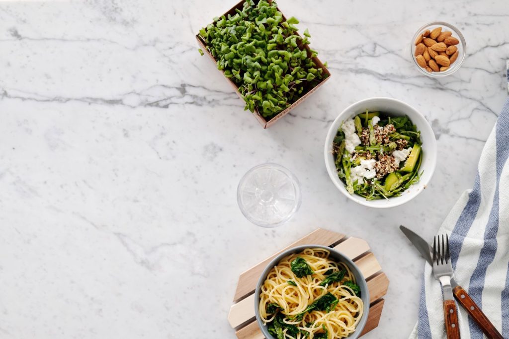 Flat lay of a nutritious meal with salad and pasta on a marble surface, perfect for healthy eating themes.