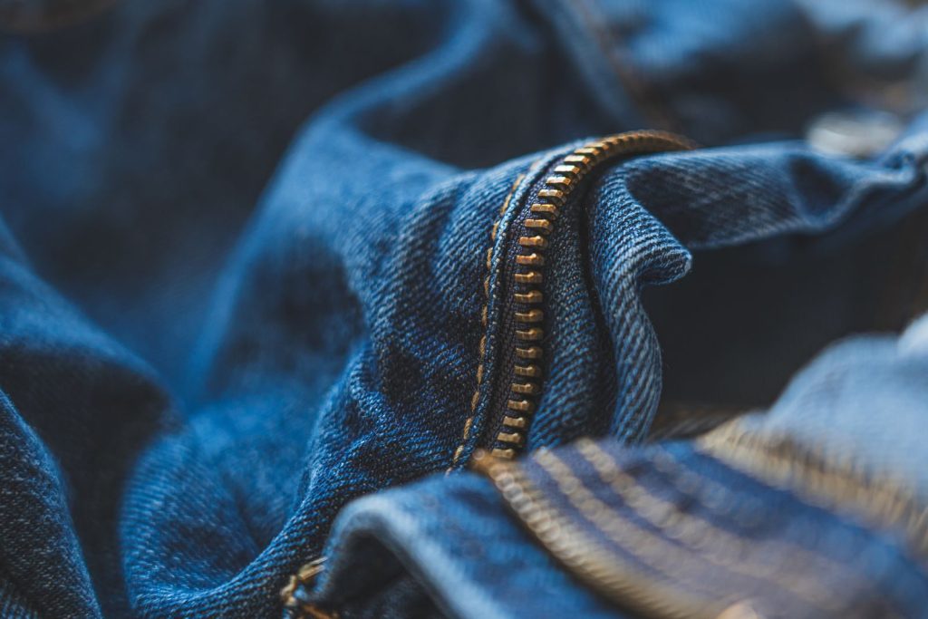 Detailed shot of blue denim fabric and zipper, highlighting texture and fashion element.