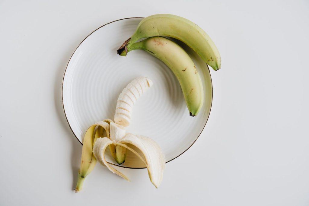 Top view of a peeled and unpeeled banana on a white plate, highlighting healthy eating.