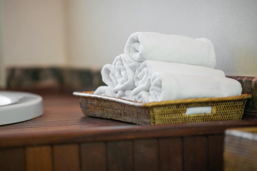 Rolled white towels neatly placed in a woven basket, perfect for spa or bathroom decor.
