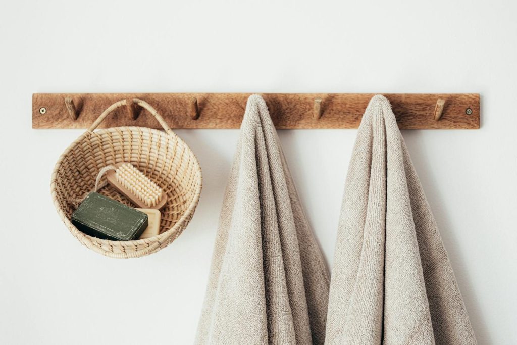 Wooden wall hanger with soft towels and wicker basket with natural spa cosmetics products