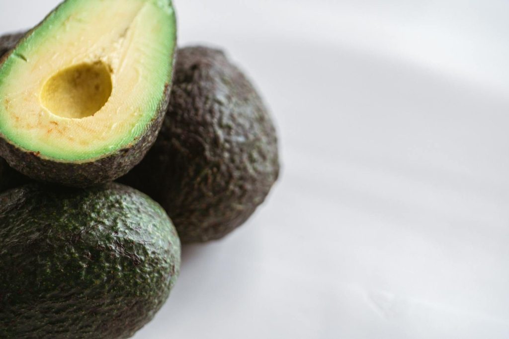 From above of similar ripe tropical avocados with rough skin and tender pulp on white background
