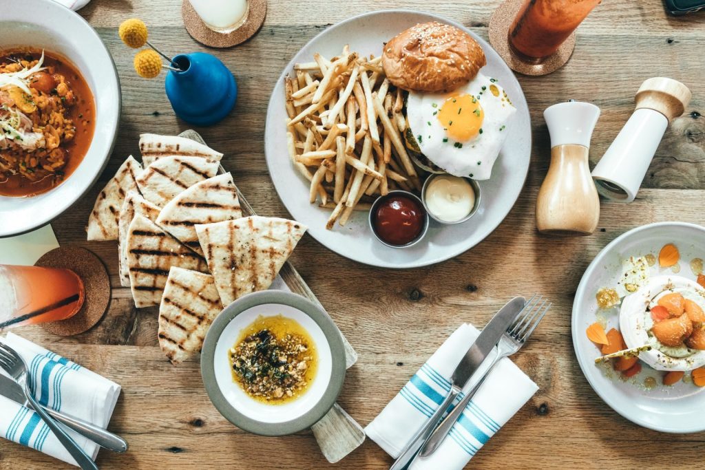 A vibrant top-view of a delicious brunch spread including fries, pita, and dipping sauces on a wooden table.