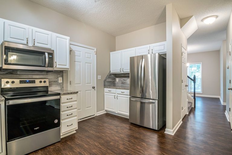 Bright modern kitchen featuring stainless steel appliances and white cabinets.