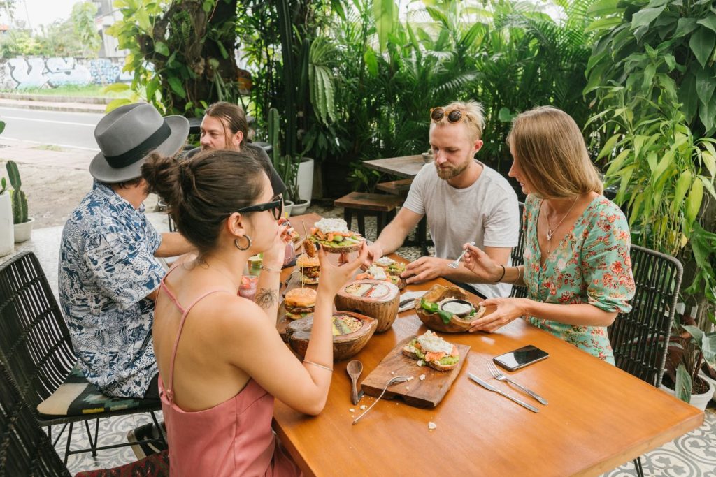 Group of friends dining on an outdoor patio, enjoying a relaxed brunch in a lush setting.
