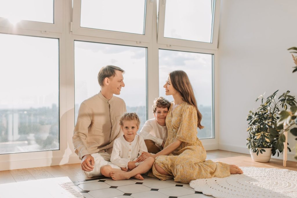 A joyful family sits together in a sunlit living room, fostering warmth and connection.