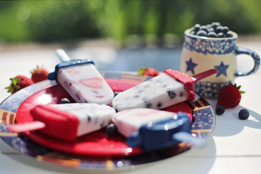 Colorful berry popsicles on a plate, perfect for a summer day. Ice cream treats with strawberries and blueberries.