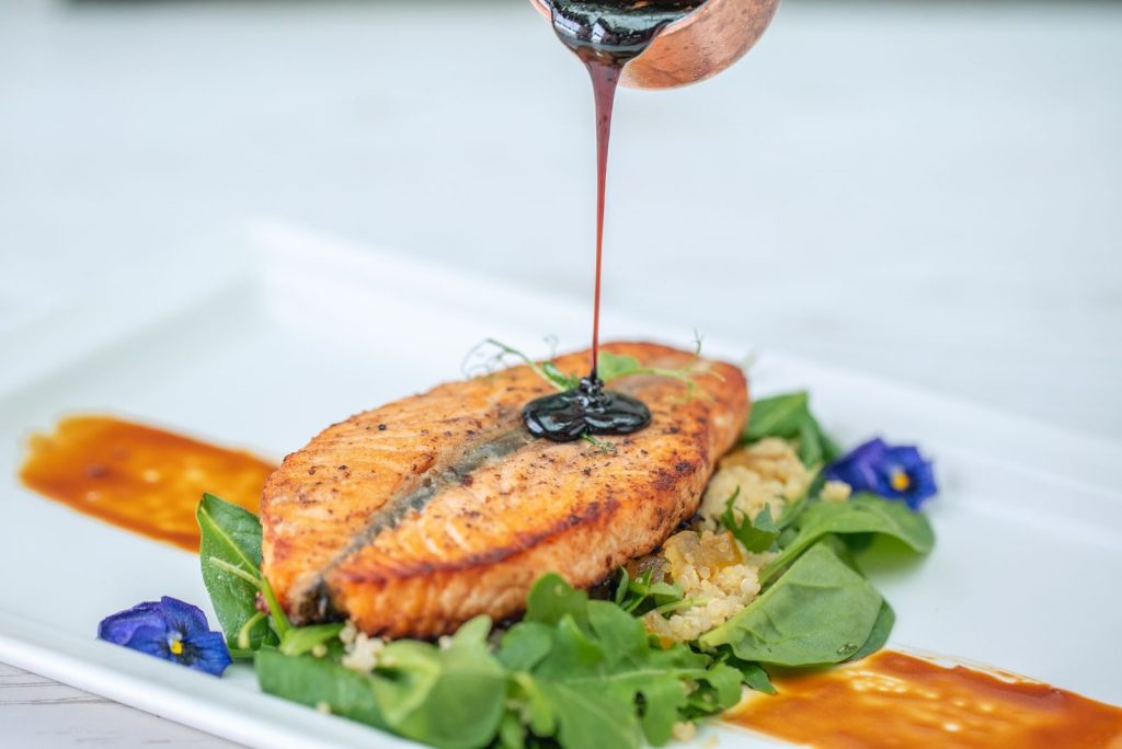Delectable grilled salmon with balsamic glaze over fresh greens and edible flowers.