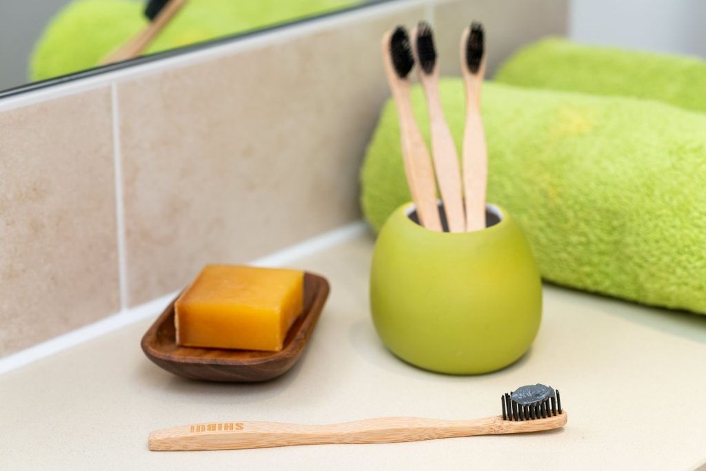 Sustainable bathroom setup with bamboo toothbrushes, soap, and a green towel.