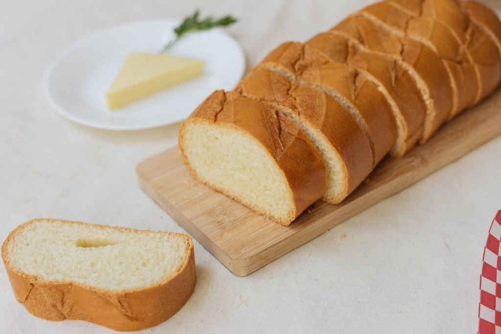 Delicious homemade white bread sliced on a wooden board, perfect for a breakfast spread.