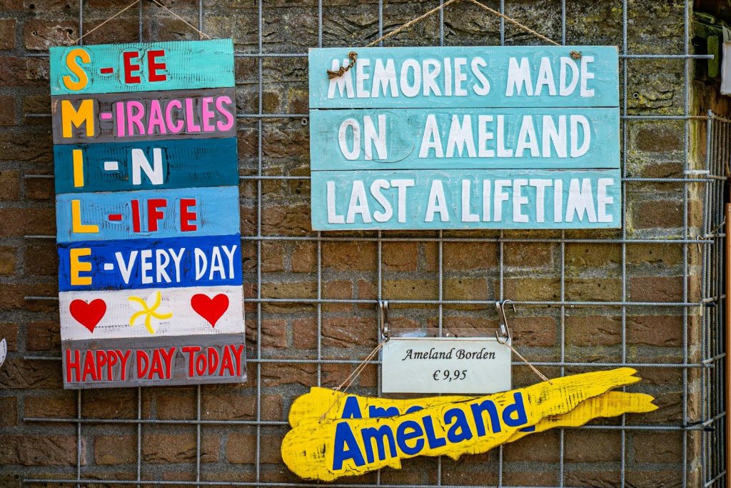 Colorful wooden signs displaying 'smile' and 'ameland' messages.
