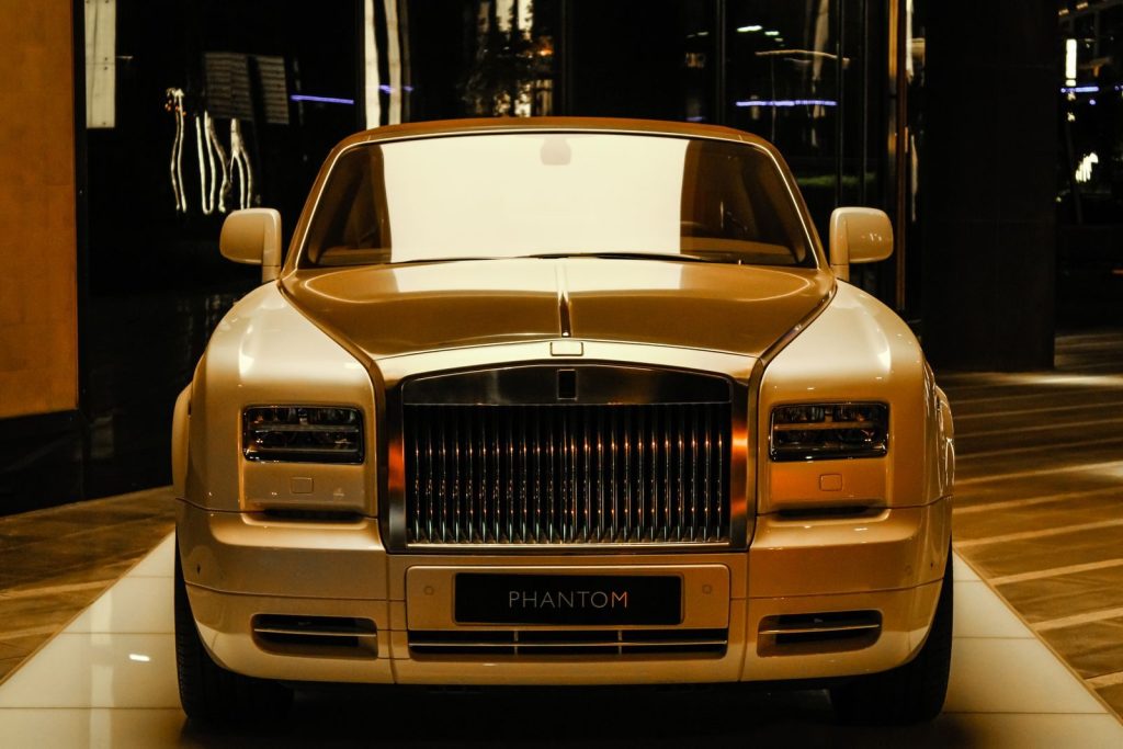Front view of a luxurious gold Rolls-Royce Phantom on display in a Dubai showroom.
