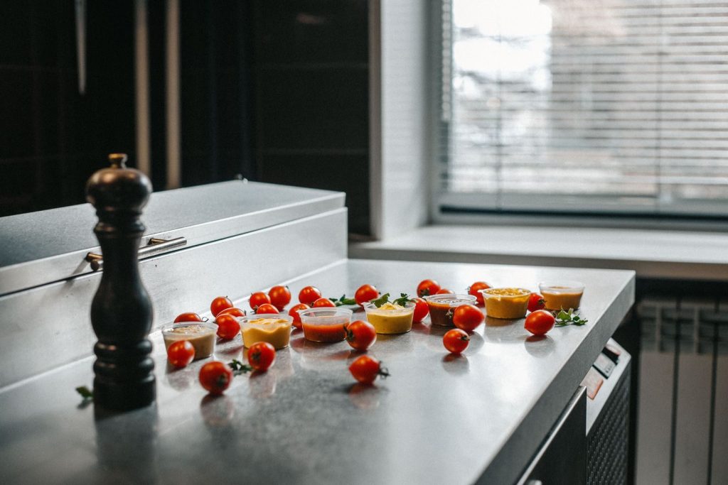 Cherry tomatoes and assorted sauces arranged on a sleek kitchen counter.