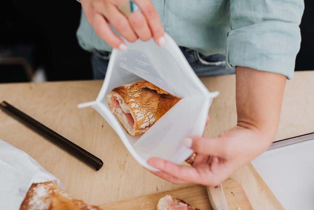 Person storing bread in a reusable silicone bag, promoting zero waste lifestyle.